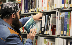 Man placing a book onto a bookshelf filled with other books